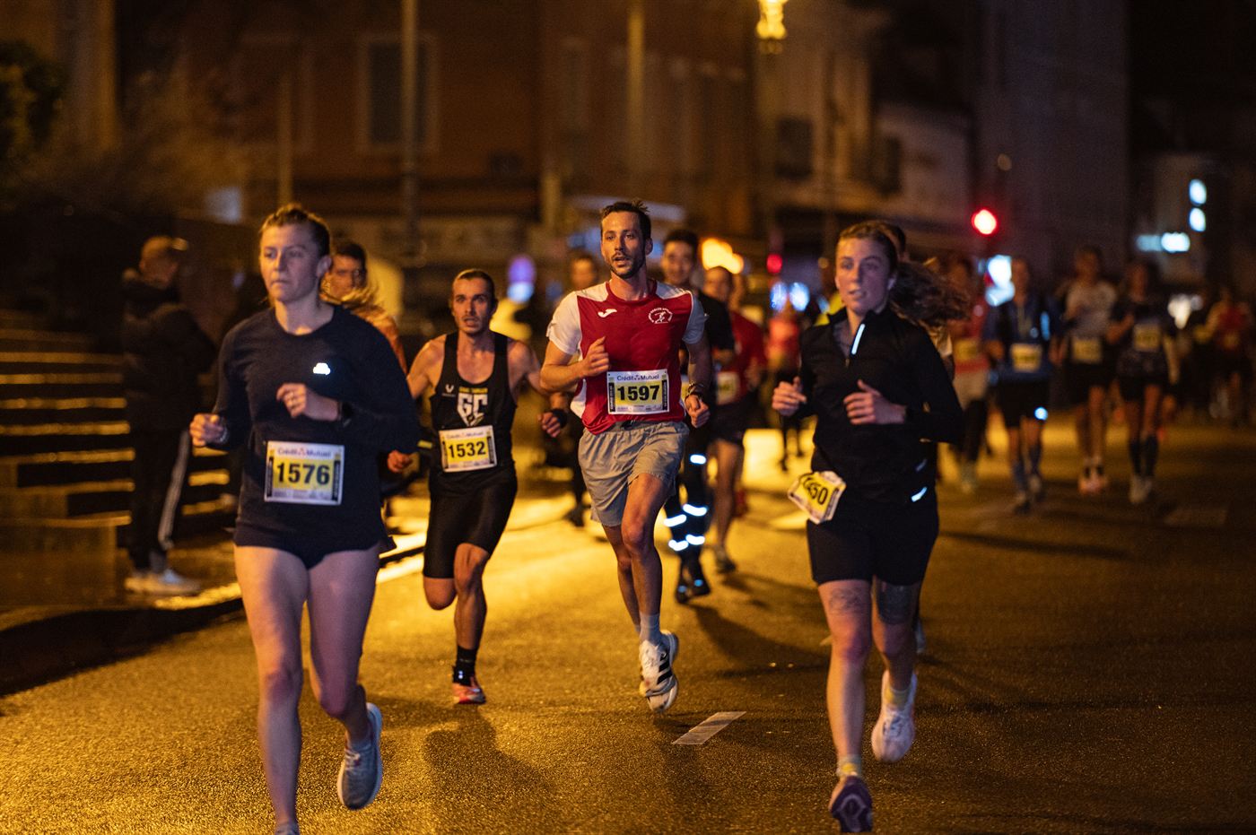 Trois coureurs en tête dans une rue sombre